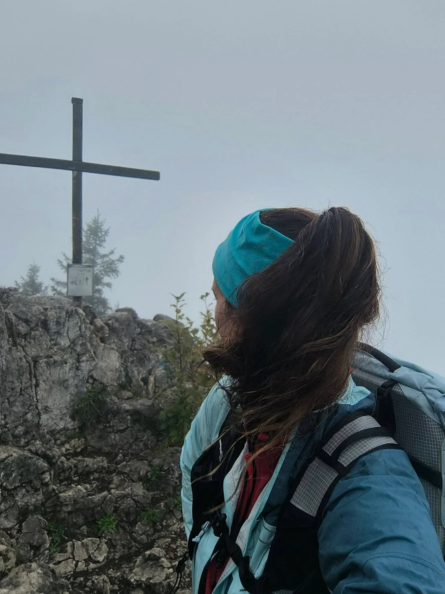 Jennifer im Nebel am Gipfelkreuz, Wind im Haar, Regenjacke — Sicht unter hundert Metern