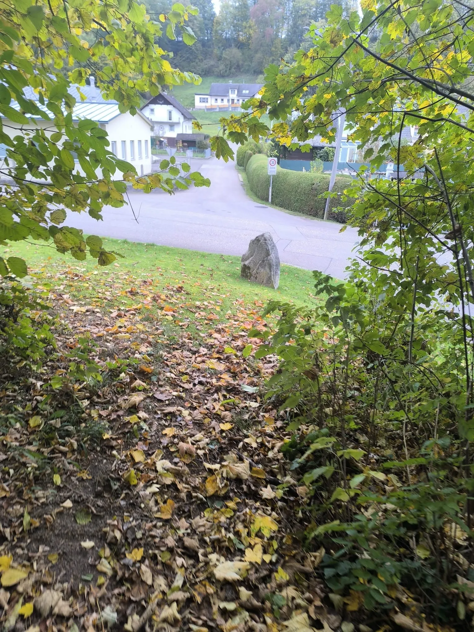 Blick vom Hang hinunter auf den Gedenkstein und die Straßenkreuzung am Ortsrand